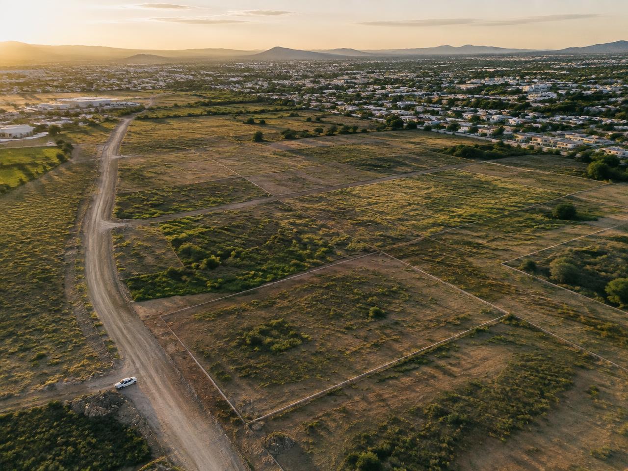 Aerial view of undeveloped land parcels at the edge of a growing city